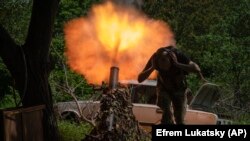 Украински войник си запушва ушите по време на минометен изстрел близо до Бахмут. 