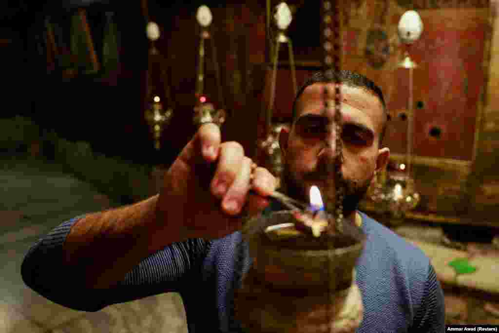 Фотографія від 2 грудня: чоловік запалює свічку в церкві Різдва Христового у Вифлеємі, де згідно з Біблією народився Ісус Христос.&nbsp; &laquo;Вифлеємський вогонь миру&raquo;&nbsp;&ndash; це австрійська ініціатива, започаткована у 1987 році. Відтоді щороку вогонь із храму Різдва Христового перевозять до Австрії національною авіакомпанією, а потім члени австрійської асоціації скаутів поширюють його по всій країні.