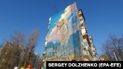 Українські військові та енергетики стоять перед муралом українським військам ППО та енергетикам. Київ, 30 листопада 2023 року