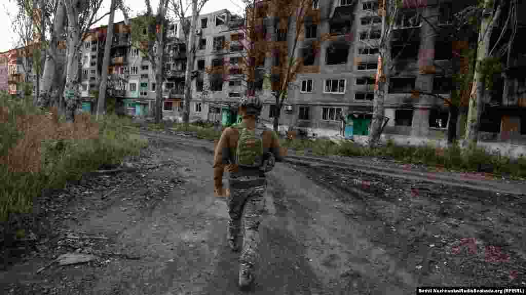 Egy katona sétál romos épületek mellett Vuhledarban. A városban egykor körülbelül tizennégyezer ember élt, most már csak néhány száz civil és az ukrán hadsereg csapatai maradtak