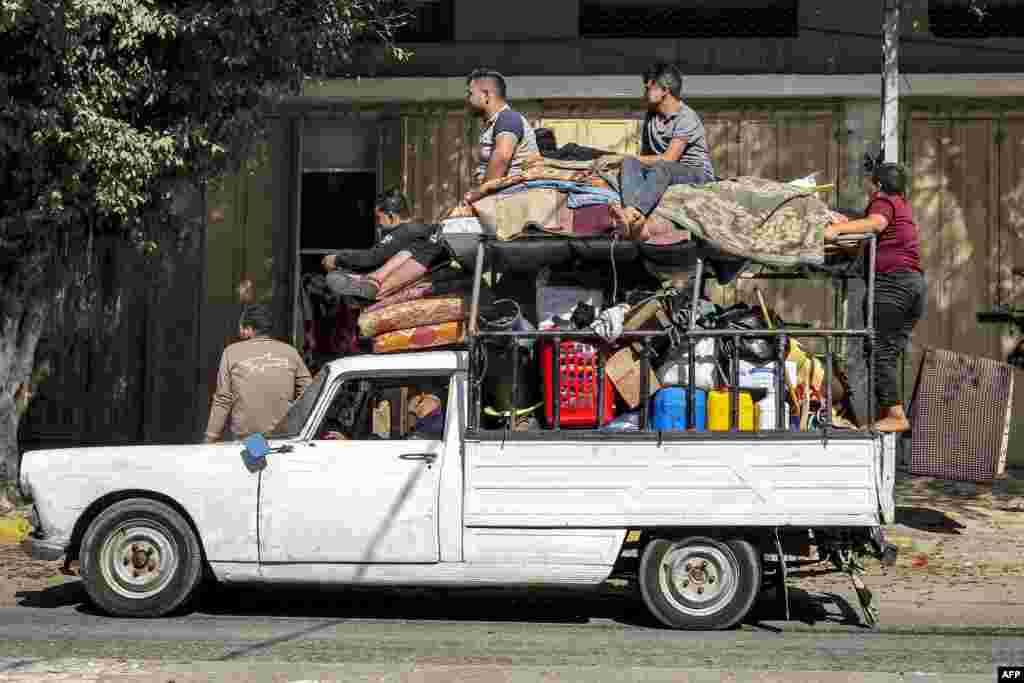 Njerëzit qëndrojnë hipur mbi gjësendet e ngarkuara në një automjet të vjetër në Rafah.