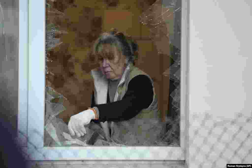 Žena čisti staklo na prozoru nakon što je zgrada oštećena u napad dronom.&nbsp;