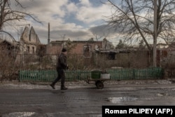 Місцевий житель Сергій везе повз зруйновані будинки візок із вугіллям для обігріву свого будинку в Лимані, 21 січня 2024 року