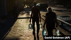 Подружжя несе пляшки з водою у Покровську, Донецька область, Україна, 4 серпня 2022 року. Фото архівне