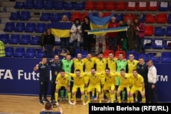 Reprezentacija Ukrajine u futsalu i ukrajinski novinari u skloništu na Kosovu poziraju posle utakmice protiv Kosova.
