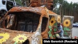 Artă pe un vehicul distrus în cursul atacurilor rusești: artistul american Trek Kelly la depozitul de la Irpin, Ucraina, 10 august 2022. 2022. 