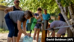 Meštani Slovjanska se okupljaju da crpe vodu iz bunara ispred stambenog naselja u tom gradu, 6. avgusta 2022.