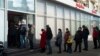 Russia - People stand in line to withdraw money from an ATM of Alfa Bank in Moscow, Russia, Sunday, Feb. 27, 2022. Russians flocked to banks and ATMs shortly after Russia launched an attack on Ukraine and the West announced crippling sanctions. (AP Photo/