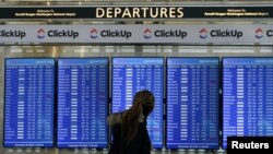 Putnik gleda na tablu sa rasporedom letova na nacionalnom aerodromu Ronald Reagan u Washingtonu u Arlingtonu, Virdžinija, SAD, 20. decembra 2022. 