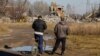 Two men watch workers removing the debris of the building in Makiyivka where the Russian soldiers were housed when the strike hit on New Year's Eve.