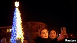 Две жени се снимат пред коледната елха в центъра на Киев
