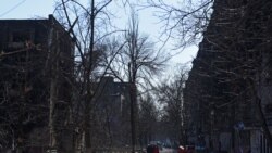 Localnicii din Mariupol merg pe lângă clădirile dărâmate de bombardamentele rușilor.