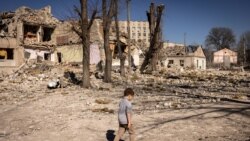 Un copil merge în fața unei școli avariate în orașul Jîtomir, în nordul Ucrainei, 23 martie 2022.