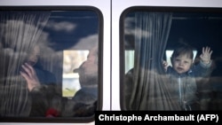 Un copil ucrainean face cu mâna dintr-un microbuz care transportă refugiați preluați de la punctul de frontieră Palanca, 12 aprilie 2022 