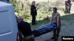 Criminaliștii transportă către ambulanță cadavrul unei fete ucise în timpul unui atac cu rachete rusești pe 1 iunie, în Kiev.