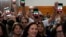 People hold up phones displaying the words "Free Iran" as President Joe Biden addresses a crowd in San Diego on November 3.