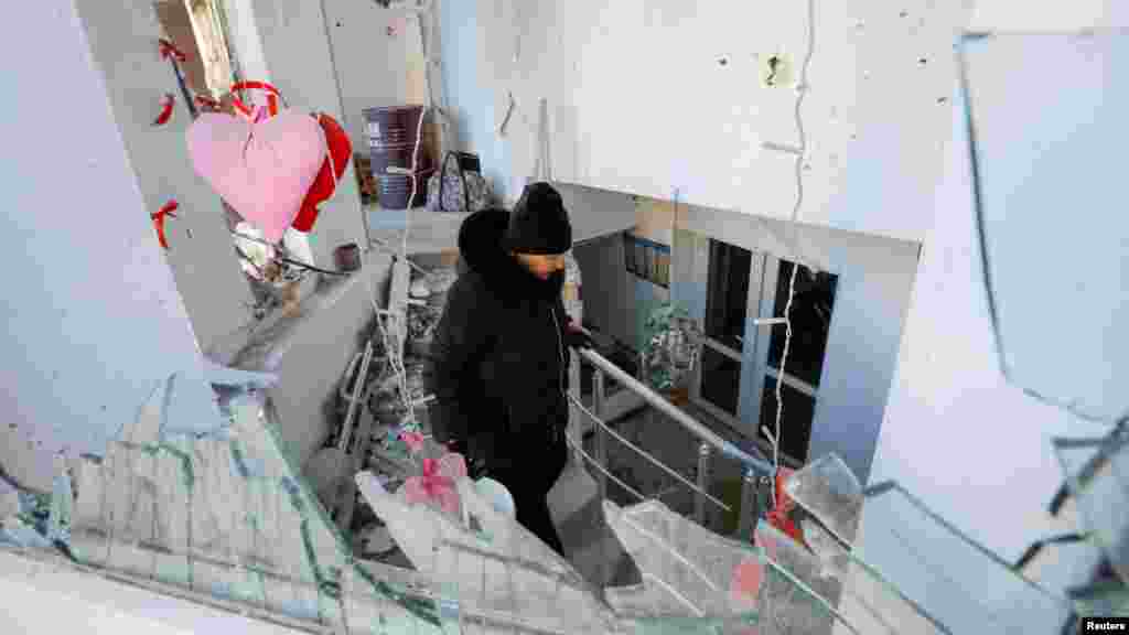 Egy nő a törmeléket távolítja el egy lakóépületben található kávézóból, amely a közelmúltban egy ágyúzás alkalmával sérült meg Donyeckben