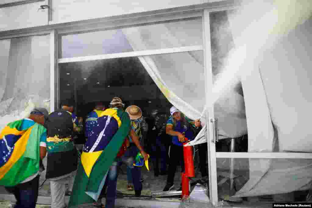 Mbështetës të Bolsonaros duke hyrë me dhunë një ndërtesë gjatë një demonstrate kundër Lulas, në Brazili, më 8 janar 2023.