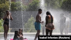 Disa persona duke u freskuar në një park në Madrid, gjatë valës së të nxehtit në Spanjë në korrik të vitit 2022.