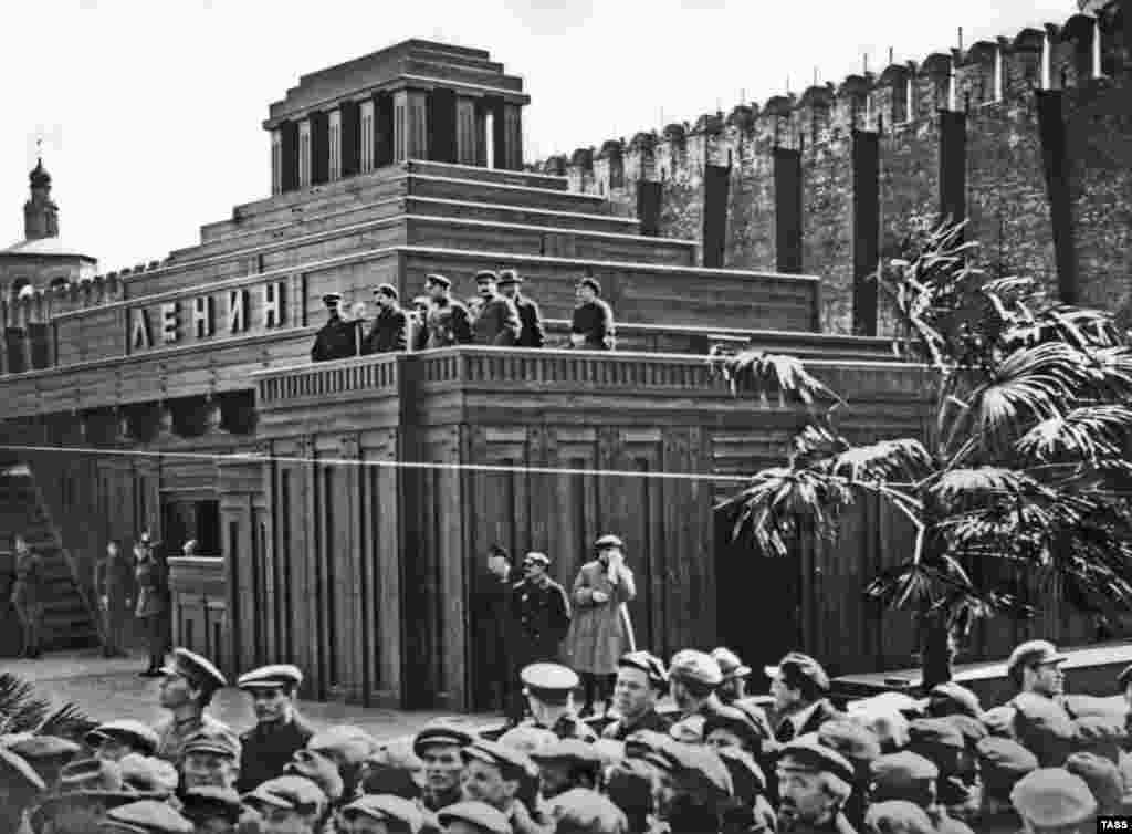 Liderii bolșevici, inclusiv Iosif Stalin (al treilea din dreapta, privind spre cameră), pe platforma oficială a celui de-al doilea mausoleu, în 1926.&nbsp; În martie 1924, acest mausoleu din lemn, de mai mari dimensiuni, a fost construit tot de Șciusev. Primul proiect întâmpinase mai multe dificultăți. Fiind mai mic, capriciile vremii și căldura generată de fluxul continuu de oameni care se perindau pe acolo riscau să ducă la putrezirea rămășițele lui Lenin.