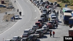 Люди и автомобили на дороге в сторону КПП "Верхний Ларс" на российско-грузинской границе