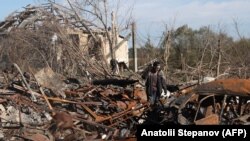 Egy helyi lakos háza és kocsija romjainál Kupjanszkban, a harkivi területen 2022. október 17-én