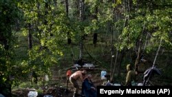 Egy ukrán katona haját vágják az erdőben a visszafoglalt Liman mellett 2022. október 3-án