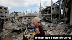 Palesztin nő gyerekével Gázában 2021. május 23-án a romoknál, amelyek a házukból maradtak a Hamász és Izrael közötti rakétaháború közepette
