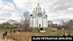 Műanyag zsákokba csomagolt holttestek a bucsai templomudvaron ásott tömegsírban 2022. április 4-én