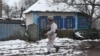 Ukraine -- A soldier walks past an abandoned house