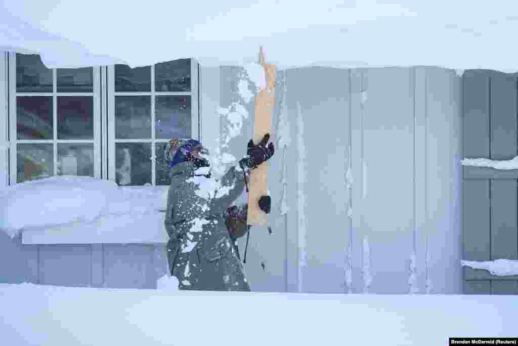 Bár vasárnap feloldották a hivatalos hóviharriasztást Buffalo nagy részén, a hatóságok arra figyelmeztettek, hogy egyes területeken keddig még több hó várható. A fotón egy férfi próbálja leverni a havat háza tetejéről a vihar után, december 25-én Amherstben