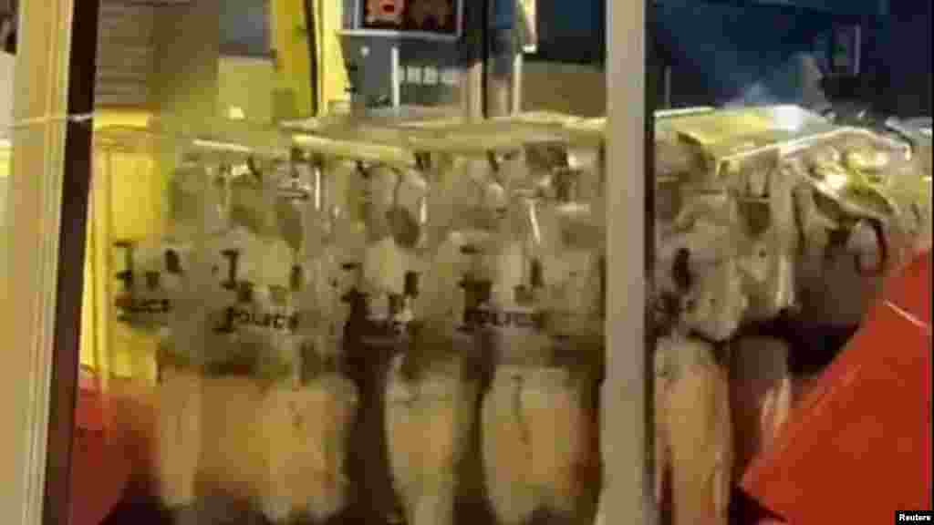 Ezen a közösségi médiában terjedő videóból kivágott képen rohamrendőrök védőruhában, pajzsot tartva, alakzatban vonulnak a demonstrálók ellen