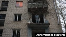 Un bărbat se uită la distrugerile din apartamentul avariat al unei clădiri rezidențiale din Herson