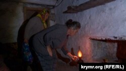 Марина Серединова та Наталя Трентинець у підвалі запалюють гасову лампу під час російського обстрілу