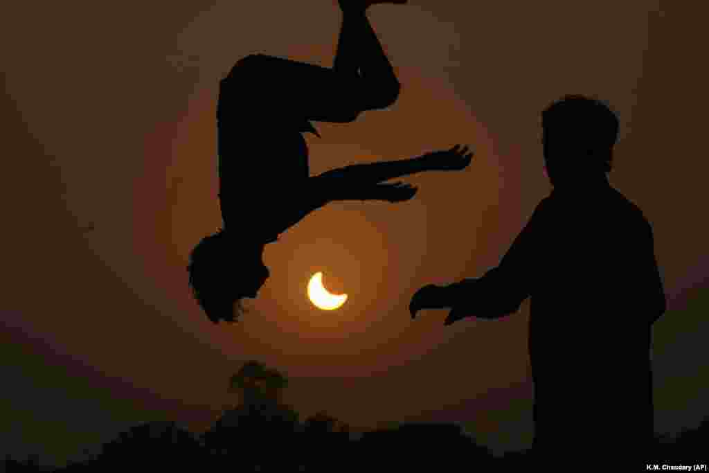 Djelomično pomračenje Sunca uokvireno je mladima koji skaču na trampolinu u predgrađu Lahorea, u Pakistanu, 25. oktobra.