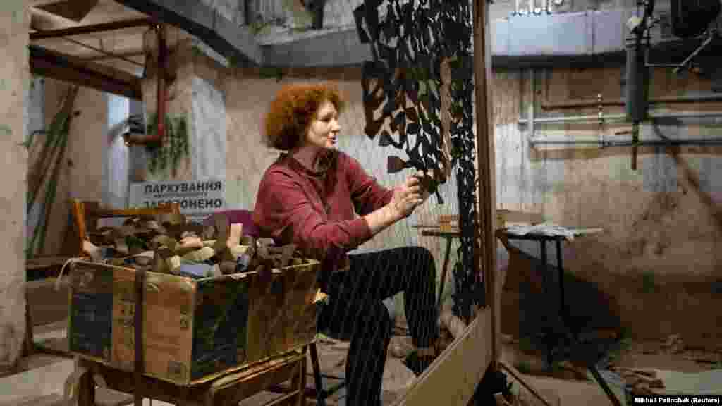 Egy kijevi bunkerben álcázásra használható hálót sző egy önkéntes, a fotó még áprilisban készült. Az álcaháló elrejti mind a járműveket, mind a gyalogságot a drónkamerák elől.