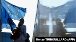 Një grua duke kaluar pranë flamujve të Bashkimit Evropian, Bruksel - Fotografi ilustruese nga arkivi.