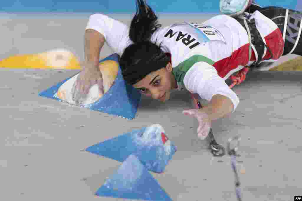 Jelképes pillanat, amint a falmászónő hosszú haja szinte hozzáér a hátán lévő Irán felirathoz.