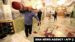 Workers clean up the scene of a deadly armed attack at the Shah Cheragh mausoleum in the Iranian city of Shiraz on October 26.