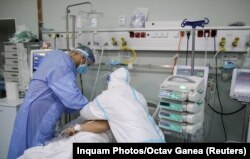 Medicul Claudiu Ruscu și o asistentă așezând masca de oxigen pe fața unui pacient Covid în stare gravă. Bântuiți de neîncredere în autorități, mulți români nu numai că nu se vaccinează, dar ajung la spital în stadii avansate ale bolii. Așa se explică și rata mare de decese.