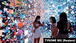 بازدیدکنندگان در مقابل یک چیدمان هنری چندبعدی با عنوان «توهمات ماشینی - فضا: متاورس»، هنگ‌کنگ، ۲۰۲۱