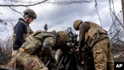 Українські військовослужбовці бригади НГУ «Хартія» заряджають снаряд у гаубицю M101 перед обстрілом російських позицій у Харківській області, 12 березня 2025 року