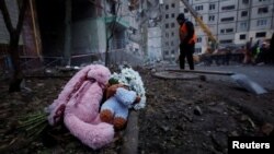 Местни хора оставиха плюшени играчки и цветя пред разрушения от руска атака блок в Днипро, Украйна