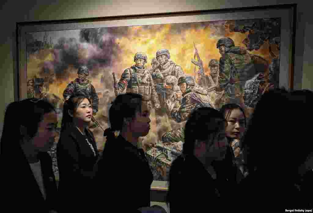 Північнокорейські туристи поруч із картиною «Героїчні борці за гідність і честь Батьківщини». У верхньому лівому куті видно куполи, схожі на архітектуру православних церков