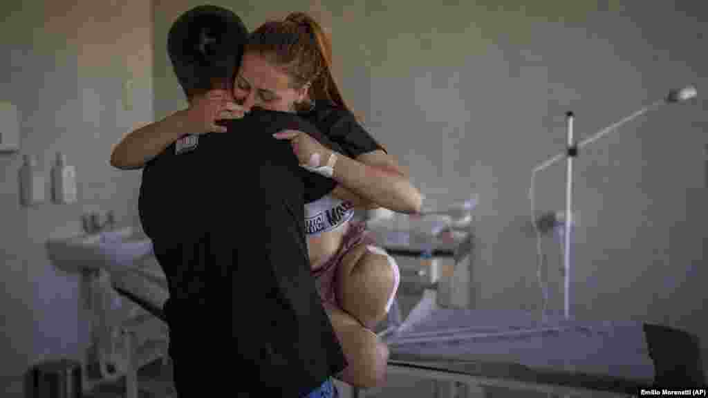 A 23 éves Okszana Balandinát öleli meg férje, Viktor egy lvivi kórházban 2022. május 13-án. Okszana mindkét lábát és bal kezén négy ujját elvesztette, amikor a háza közelében felrobbant egy gránát. &bdquo;Valami robbant. Aztán úgy éreztem, mintha rögtön utána a lábaim az ürességbe zuhantak volna. Próbáltam körülnézni, és láttam, hogy nincsenek többé, ahol korábban a lábaim voltak, ott már csak csont, hús és vér van&rdquo; &ndash; emlékezett vissza