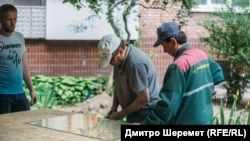 Коммунальщики в Запорожье, 25 мая 2022 года, когда российская ракета попала в ТРЦ в спальном районе