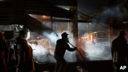 Voluntarii și pompierii continuă să stingp incendiul, după ce mall-ul din Kremenciuk a fost mombardat de ruși, 28 iunie 2022.