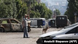 Un bărbat în apropierea unei baricade construite din două mașini răsturnate ale poliției ucrainene în orașul Lisiceansk, un punct strategic al bătăliei pentru Donbas