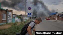 Мъж бута колелото си до пазара в Славянск, Донецка област, докато руският обстрел на града продължава. 5 юли 2022 г.
