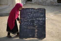 Девочка у школьной доски в афганской провинции Нангархар, февраль 2021 года. Из-за нехватки помещений школьные занятия в Афганистане часто приходится проводить на открытом воздухе